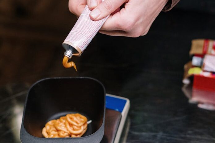 Person Holding White Paper Near Black Ceramic Bowl With Brown Food