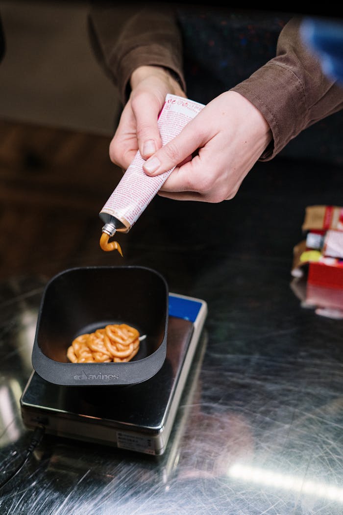 Person Holding White Paper Near Black Ceramic Bowl With Brown Food